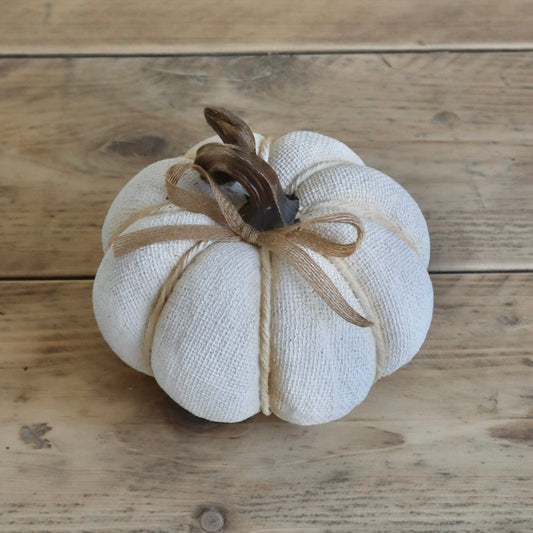 White fabric pumpkin with a brown stem on a wooden surface